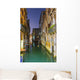 Turquoise water in a narrow canal between buildings at dusk Wall Mural