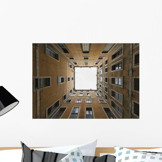 Low angle view to the sky from inside the four walls of a building Wall Mural