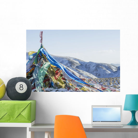 Snowy landscape with prayer flags on a high altitude mountain pass Wall Mural