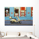 A motorized scooter parked outside a blue building along a street Wall Mural