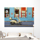 A motorized scooter parked outside a blue building along a street Wall Mural