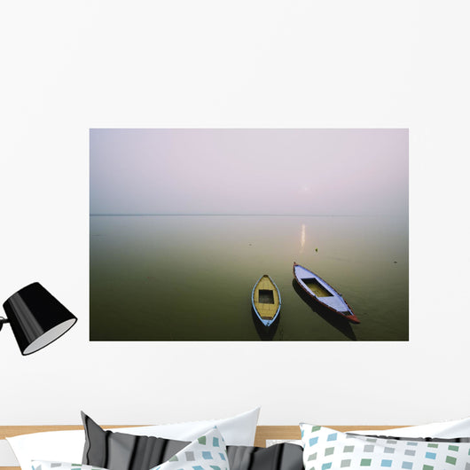 Two wooden boats sit on the tranquil water of the Ganges Wall Mural