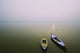 Two wooden boats sit on the tranquil water of the Ganges Wall Mural