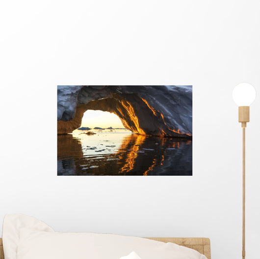 Midnight sun shines through arched iceberg near Lemaire Channel Wall Mural