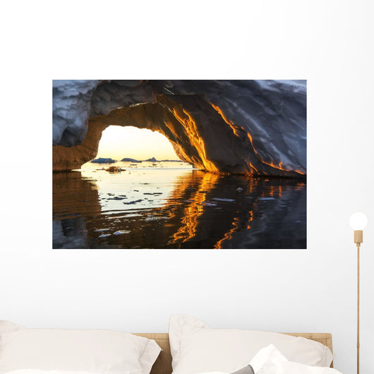 Midnight sun shines through arched iceberg near Lemaire Channel Wall Mural
