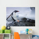 Gentoo Penguin leaping from water onto shoreline Wall Mural