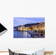 Buildings illuminated by lights along the water's edge at sunrise Wall Mural