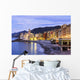 Buildings illuminated by lights along the water's edge at sunrise Wall Mural