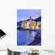 Buildings illuminated by lights along the water's edge at sunrise Wall Mural