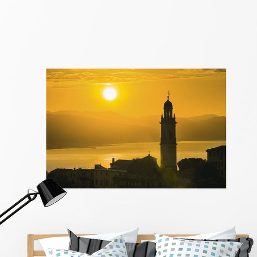 Golden sky at dusk with tower of church Wall Mural