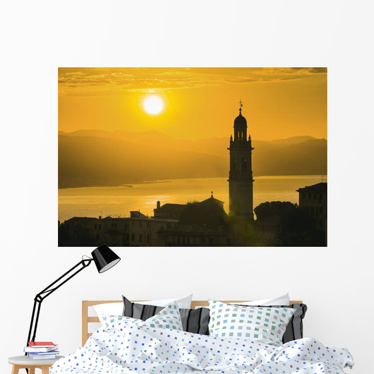 Golden sky at dusk with tower of church Wall Mural