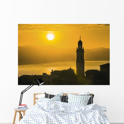 Golden sky at dusk with tower of church Wall Mural