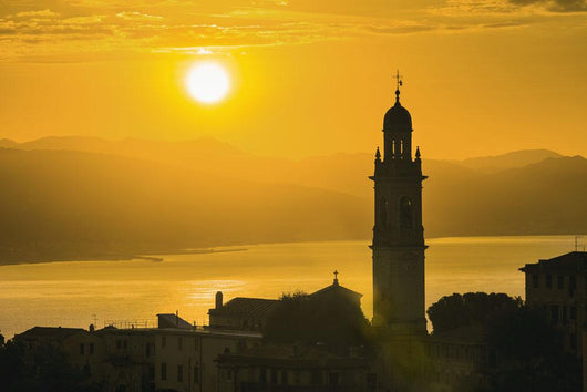 Golden sky at dusk with tower of church Wall Mural