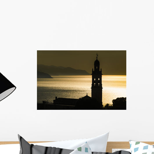 Golden sunlight reflected on water at dusk with tower of church Wall Mural