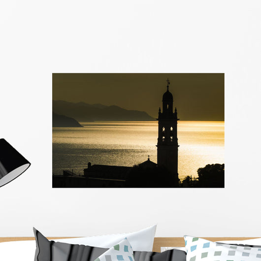 Golden sunlight reflected on water at dusk with tower of church Wall Mural