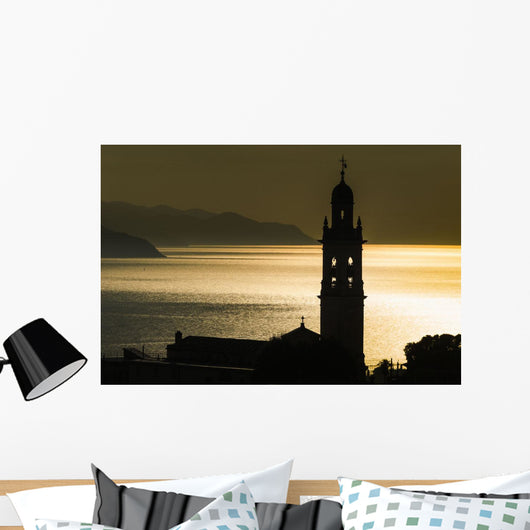 Golden sunlight reflected on water at dusk with tower of church Wall Mural