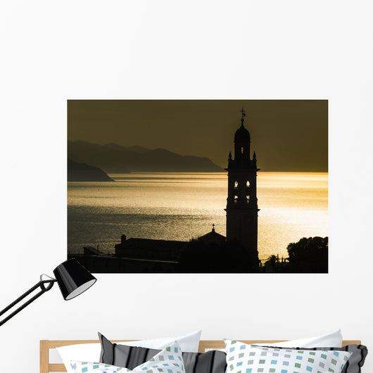 Golden sunlight reflected on water at dusk with tower of church Wall Mural