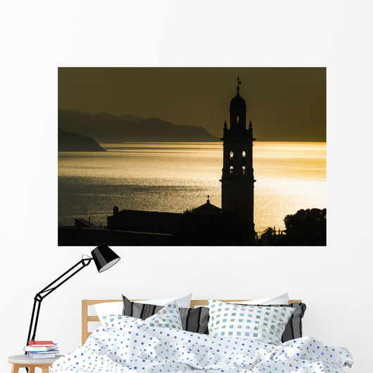 Golden sunlight reflected on water at dusk with tower of church Wall Mural