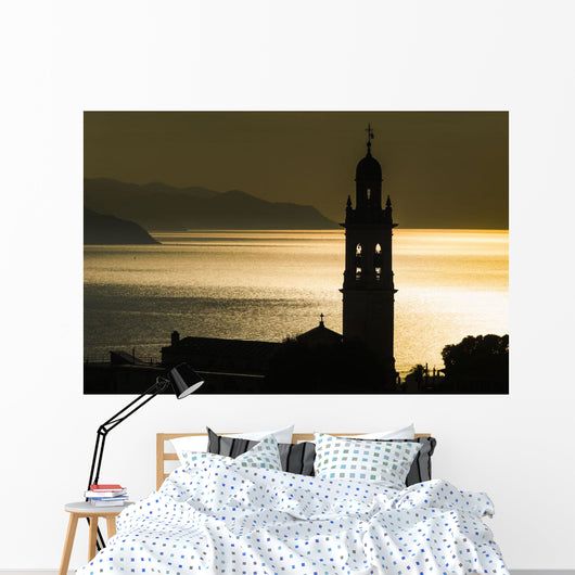 Golden sunlight reflected on water at dusk with tower of church Wall Mural