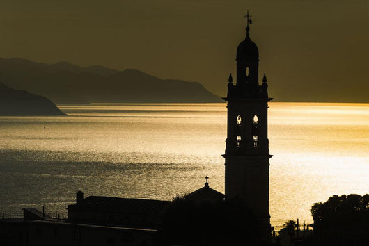 Golden sunlight reflected on water at dusk with tower of church Wall Mural