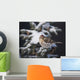 A female Common Redpoll perches on a snowy spruce tree on a cold day Wall Mural