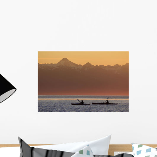 Two female sea kayakers enjoy a warm summer evening while paddling Wall Mural