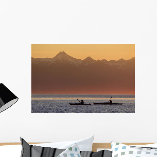 Two female sea kayakers enjoy a warm summer evening while paddling Wall Mural