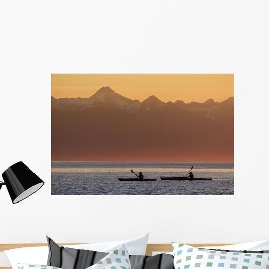 Two female sea kayakers enjoy a warm summer evening while paddling Wall Mural