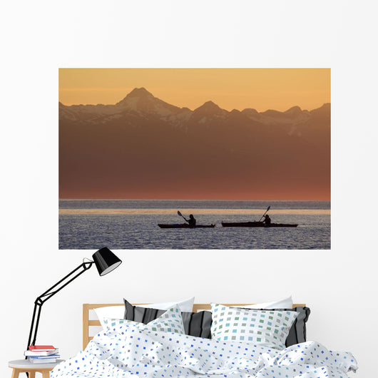 Two female sea kayakers enjoy a warm summer evening while paddling Wall Mural