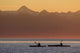 Two female sea kayakers enjoy a warm summer evening while paddling Wall Mural