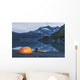 Man reading on a electronic tablet while camping with a tent and kayak Wall Mural