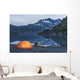 Man reading on a electronic tablet while camping with a tent and kayak Wall Mural