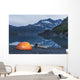 Man reading on a electronic tablet while camping with a tent and kayak Wall Mural
