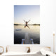 A swimmer jumps off a diving board as the sun sets over a lake Wall Mural