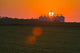 The sun sets behind a large commercial grain storage facility Wall Mural
