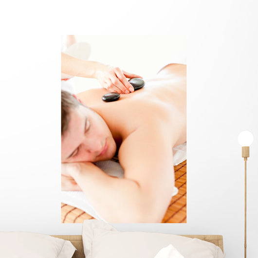 Relaxed Young Man Receiving a Back Massage with Hot Stone Wall Mural