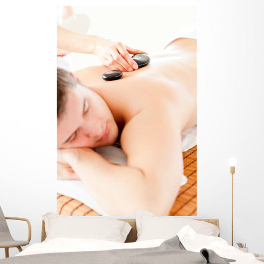 Relaxed Young Man Receiving a Back Massage with Hot Stone Wall Mural