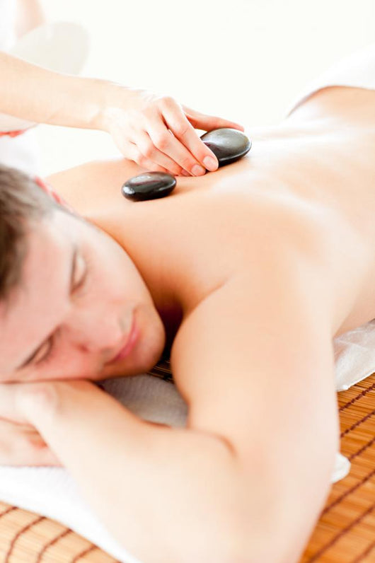 Relaxed Young Man Receiving a Back Massage with Hot Stone Wall Mural