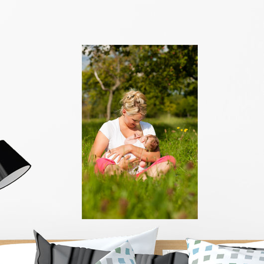 Mother nursing baby on meadow Wall Mural
