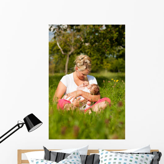Mother nursing baby on meadow Wall Mural