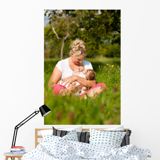 Mother nursing baby on meadow Wall Mural