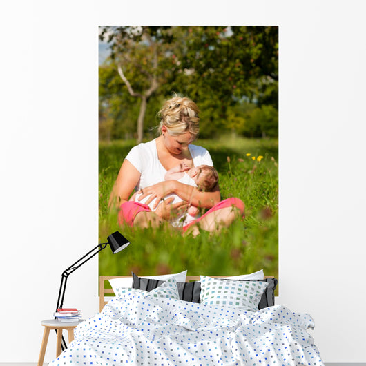 Mother nursing baby on meadow Wall Mural