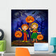 Boy and girl with pumpkins celebrates halloween. Wall Mural