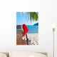 Red Santa's hat hanging on beach chair under palm tree Wall Mural