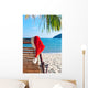 Red Santa's hat hanging on beach chair under palm tree Wall Mural