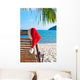 Red Santa's hat hanging on beach chair under palm tree Wall Mural