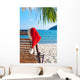 Red Santa's hat hanging on beach chair under palm tree Wall Mural
