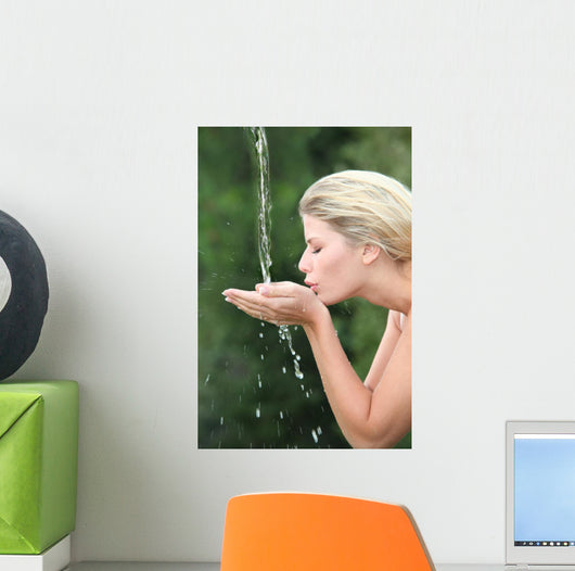 Blond woman drinking water from fountain Wall Mural