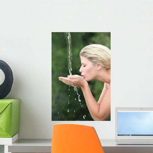 Blond woman drinking water from fountain Wall Mural