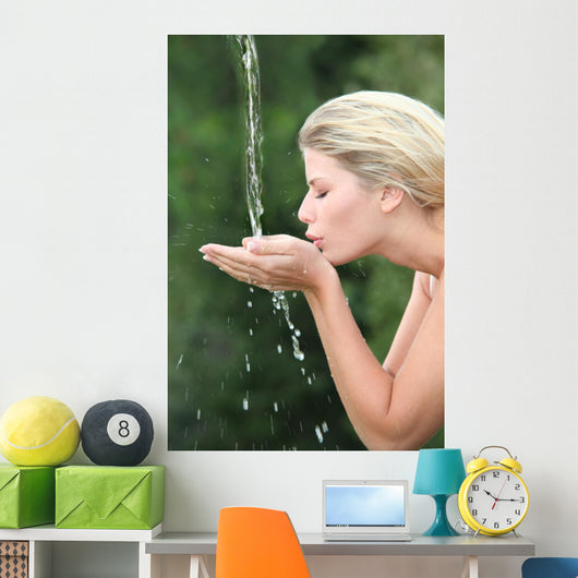 Blond woman drinking water from fountain Wall Mural